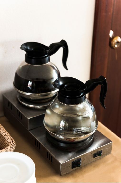A yellow kitchenaid mixer is sitting on a table next to a vase of flowers.