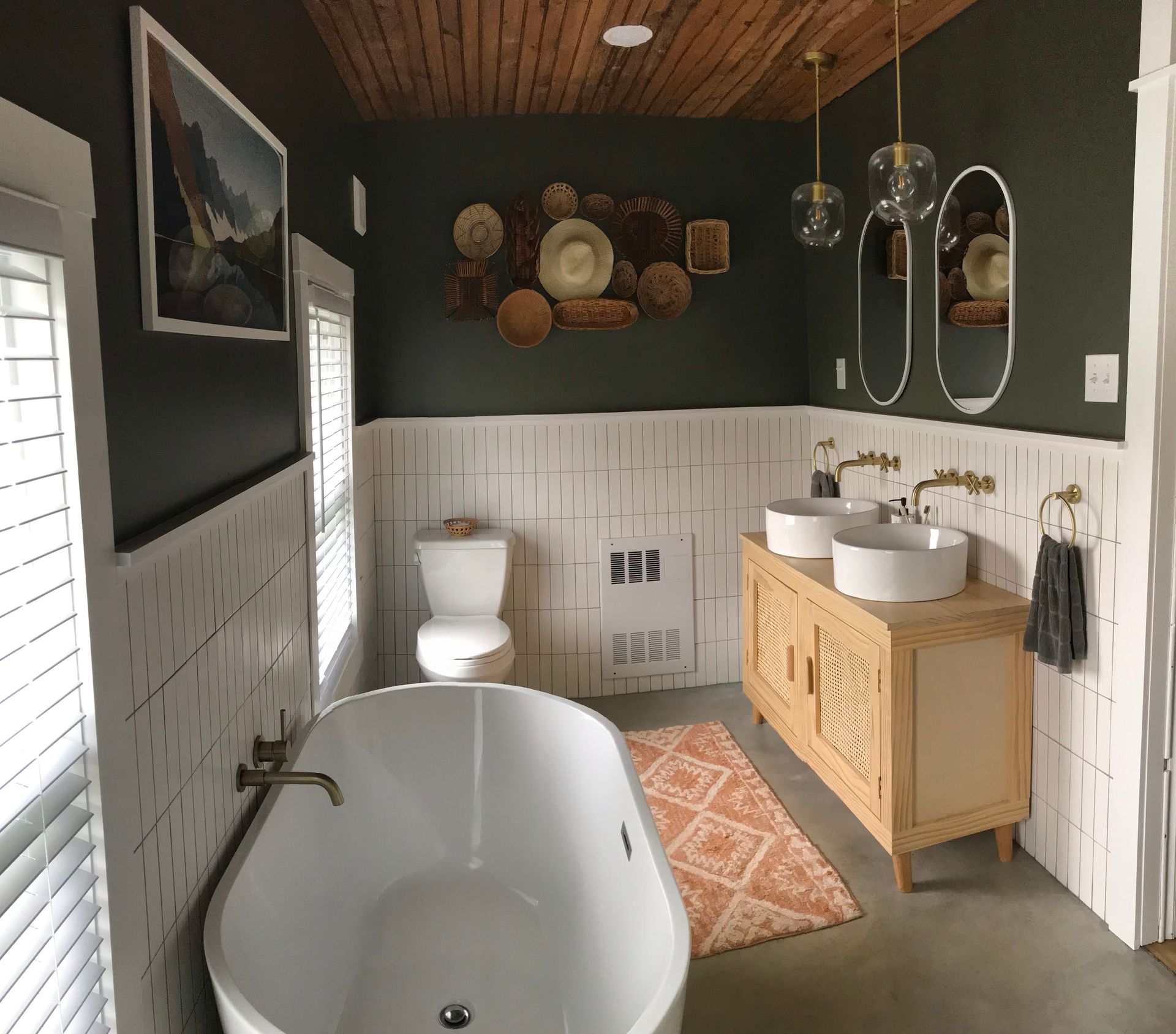 Bathroom with white tub, sink, and toilet; green walls, wood ceiling, and tan vanity.
