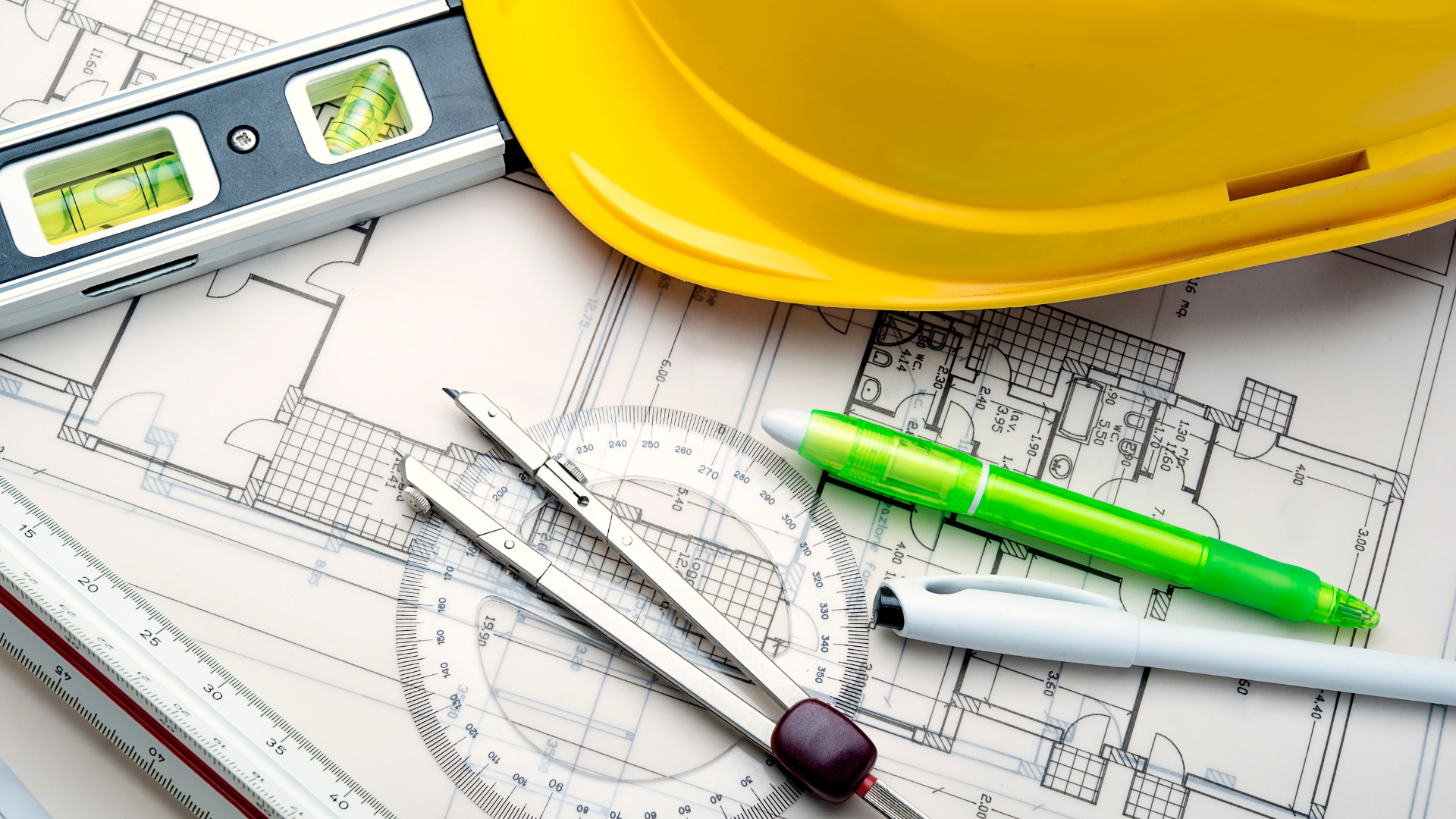 Blueprint with construction tools, including a level, hard hat, and compass.