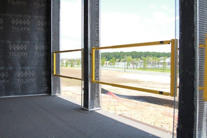 Empty modern interior with floor-to-ceiling windows and yellow safety rails overlooking a street outside