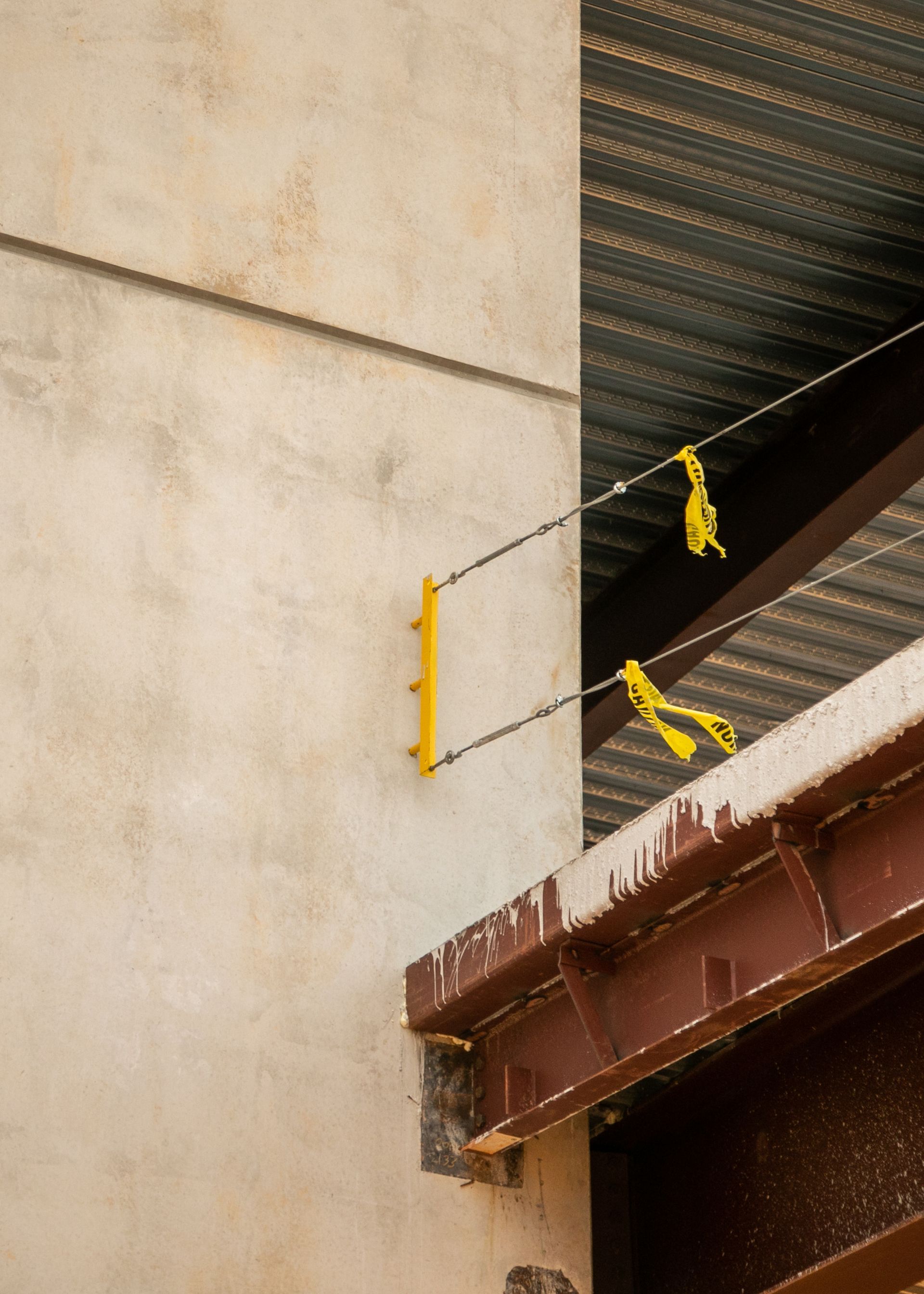 Yellow safety cables attached to a building facade above a roof edge under construction.