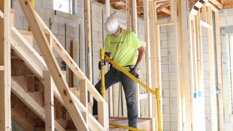 Construction worker using a drill on framing inside a house under construction