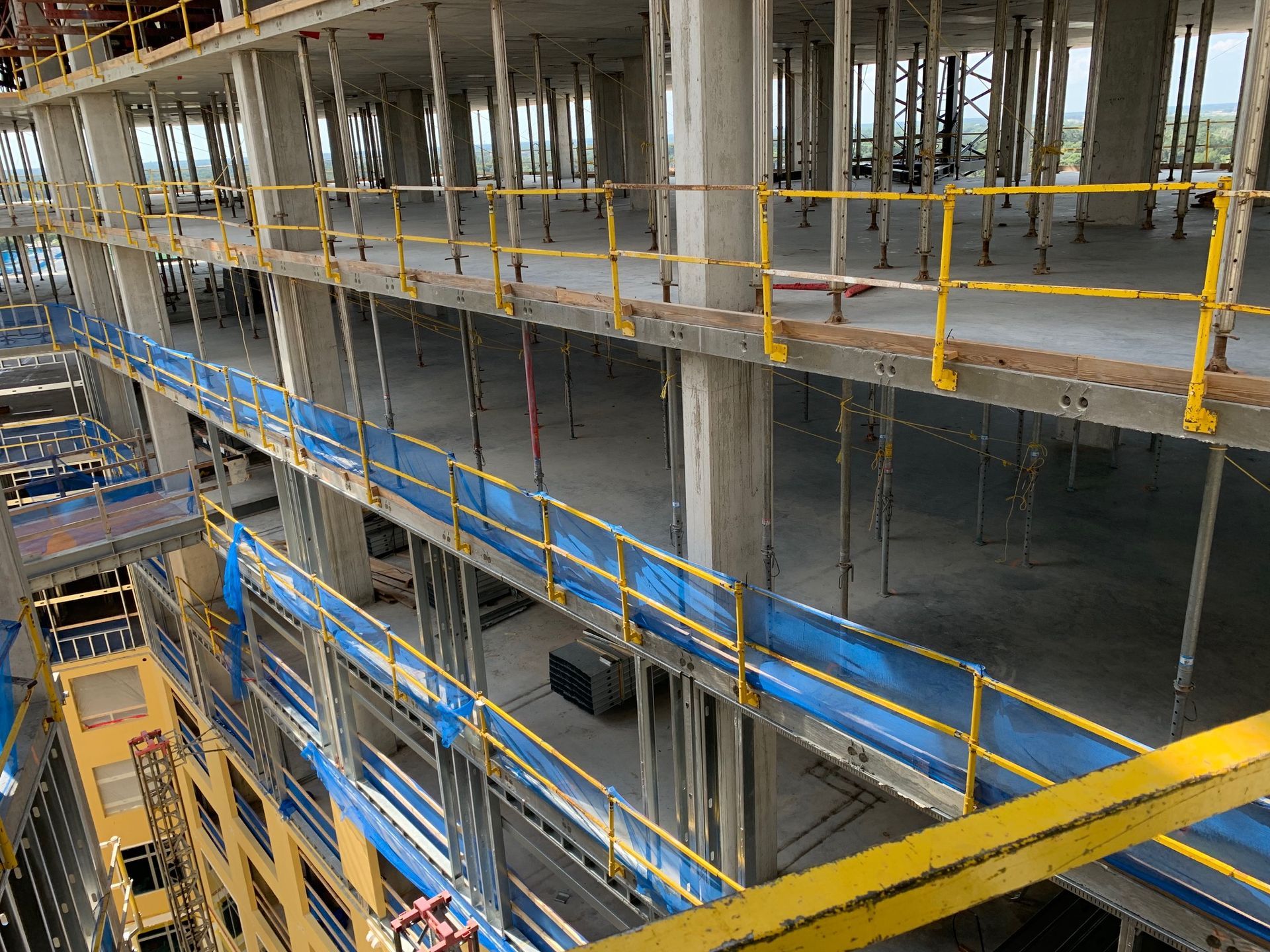 Interior of a multi-story building under construction with yellow and blue scaffolding and railings