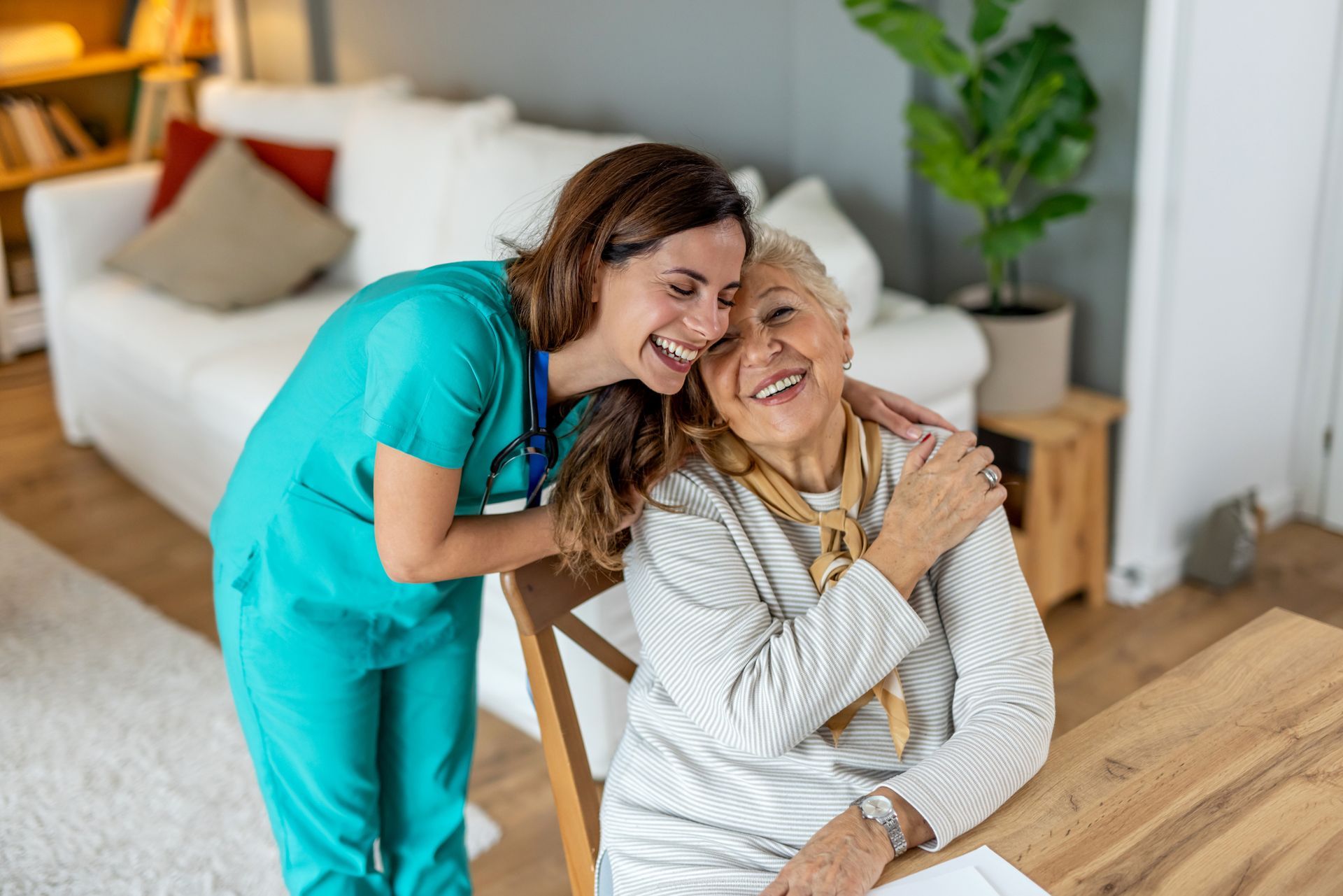 Caregiver hugging smiling senior in a home.