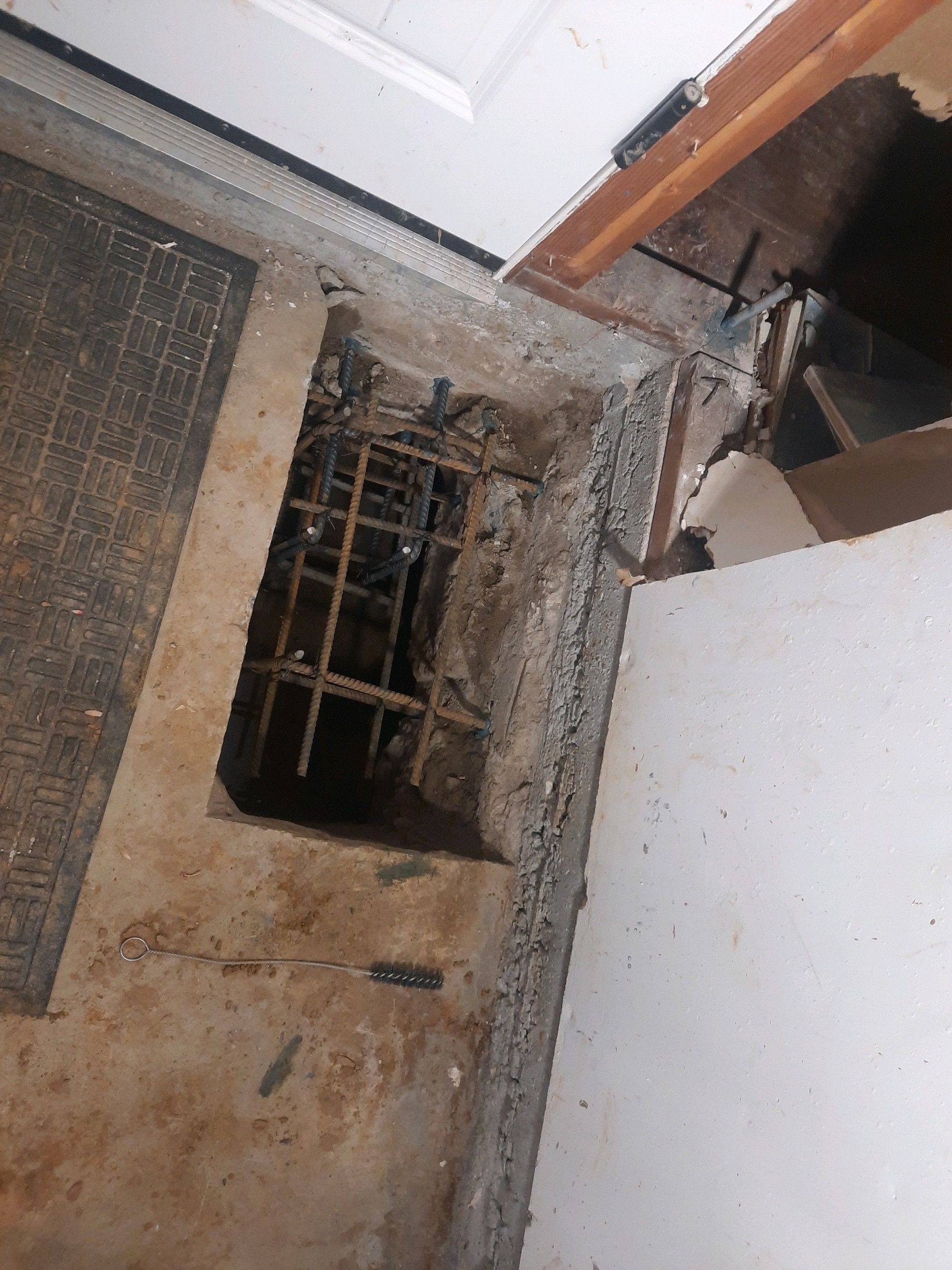 Damaged wall with a broken window and exposed wiring inside a room, viewed at an angle