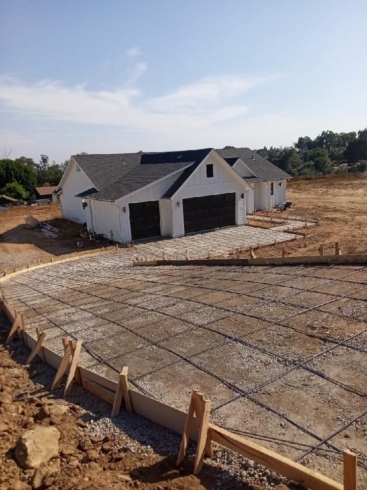 Partially built house on a dirt lot with a concrete foundation and wooden formwork in the foreground