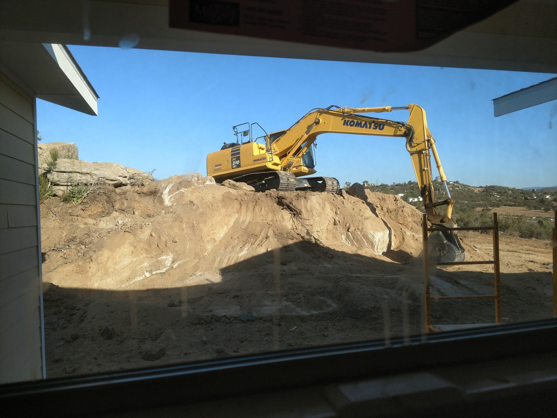 Yellow excavator digging into a sandy hillside at a construction site.