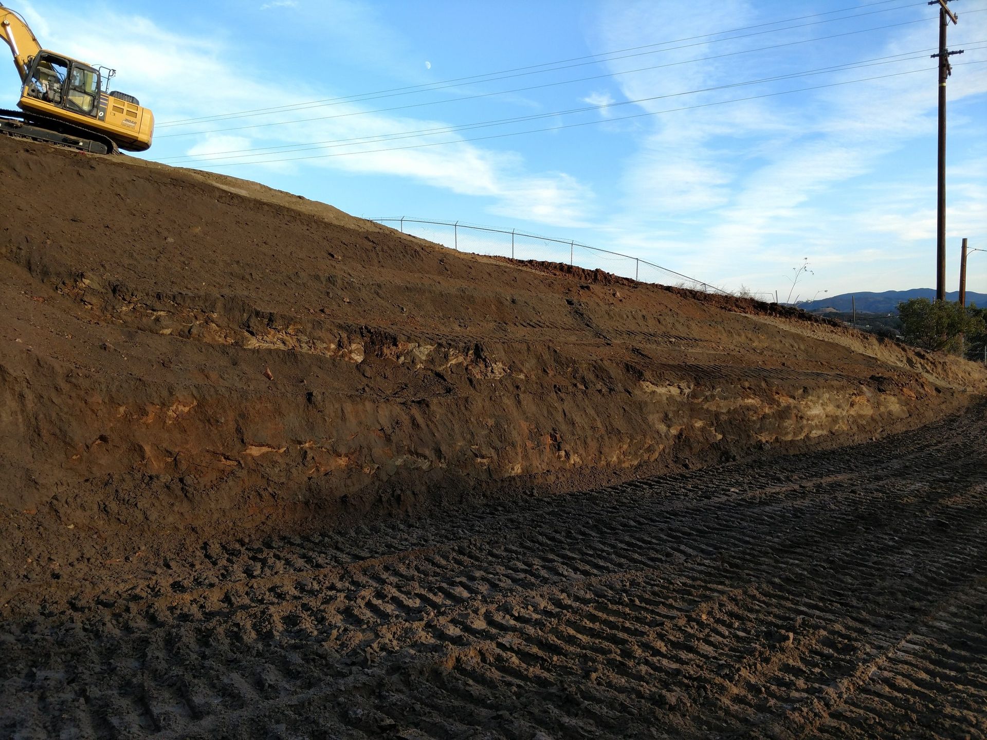 Excavator on a dirt embankment at a construction site under a blue sky