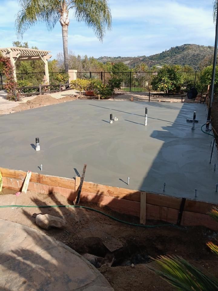 Backyard with fresh concrete patio, palm trees, and hills in the background