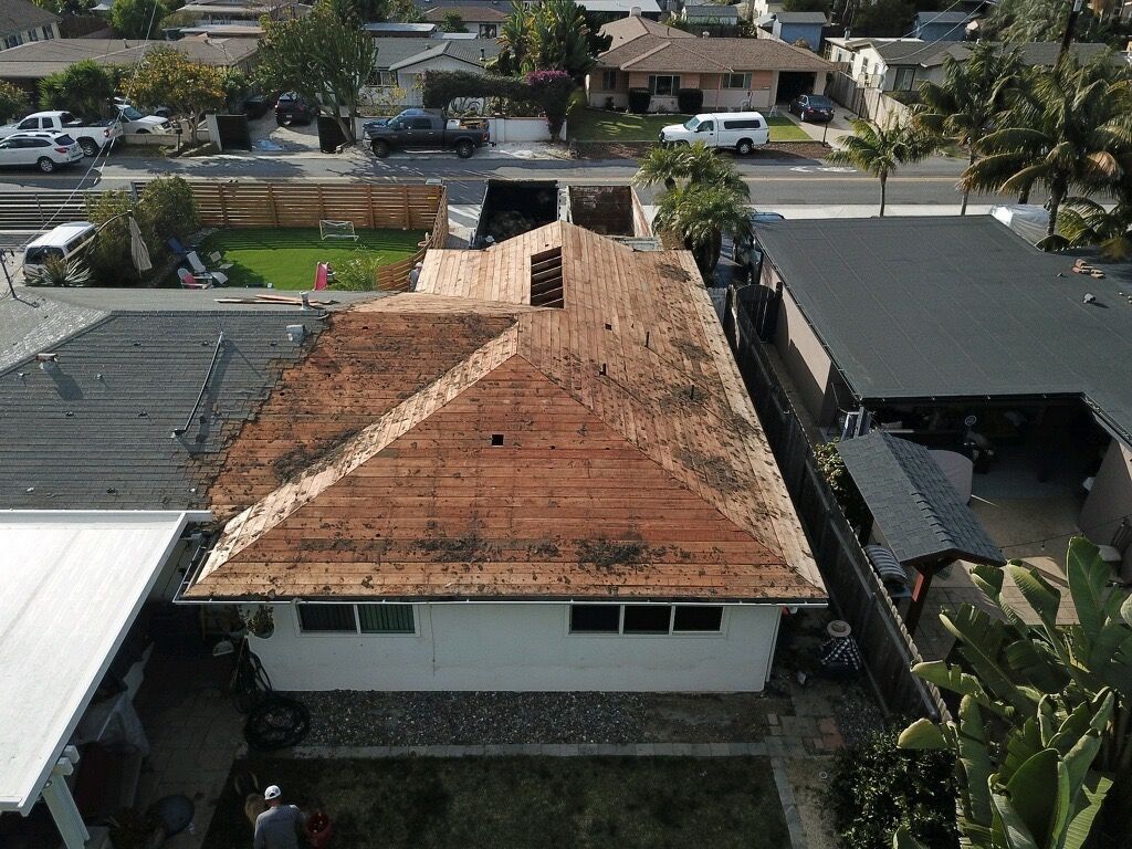 Aerial view of a house with a weathered red tile roof in a suburban neighborhood