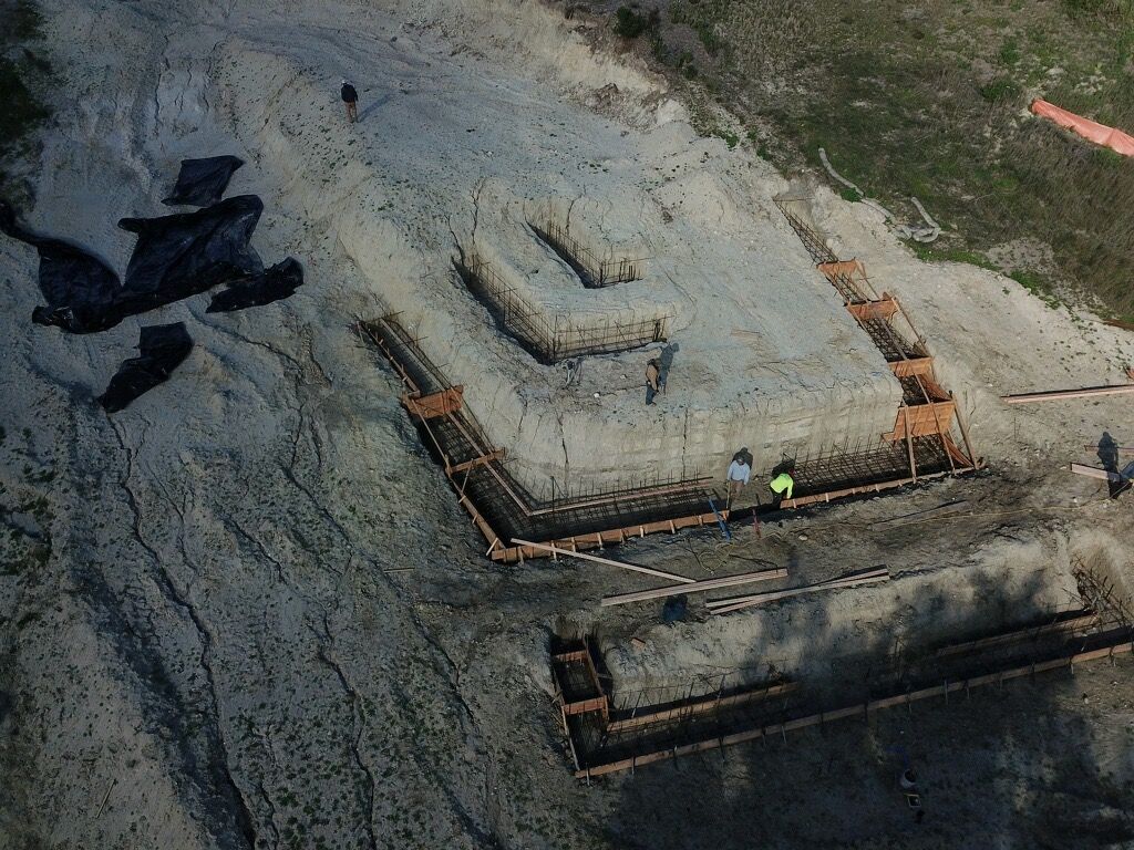 Aerial view of a construction site with concrete forms and two workers in yellow vests.