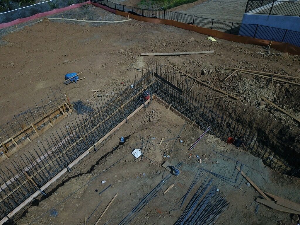 Construction site foundation excavation with rebar, concrete forms, and dirt trenches