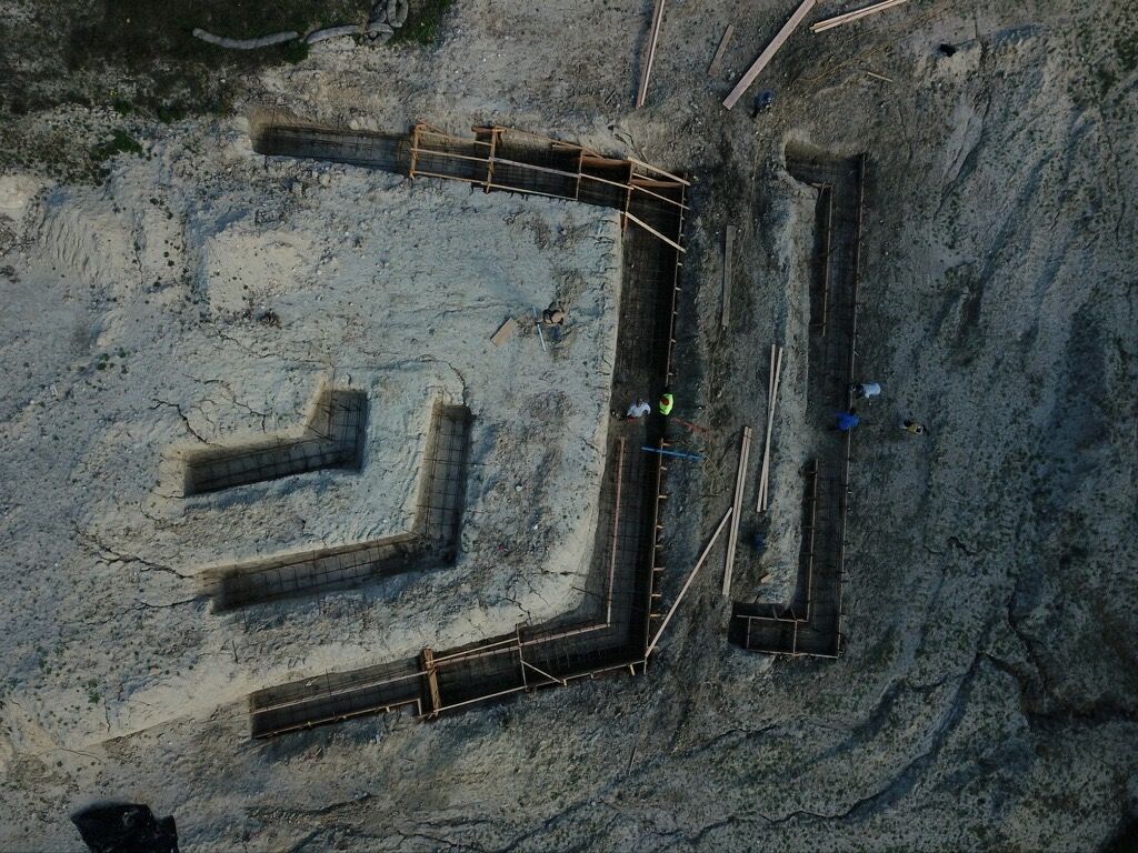 Aerial view of a rocky excavation site with an angular trench and concrete-like retaining walls.