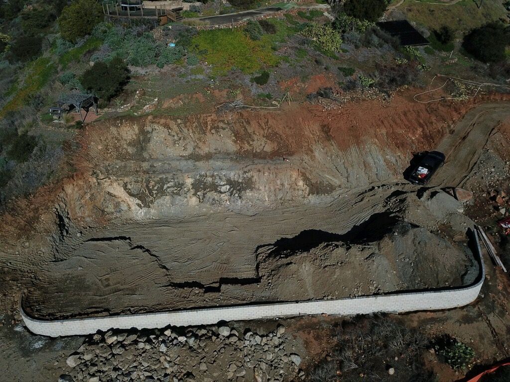 Excavated trench with exposed earth and a long white pipe running along the bottom
