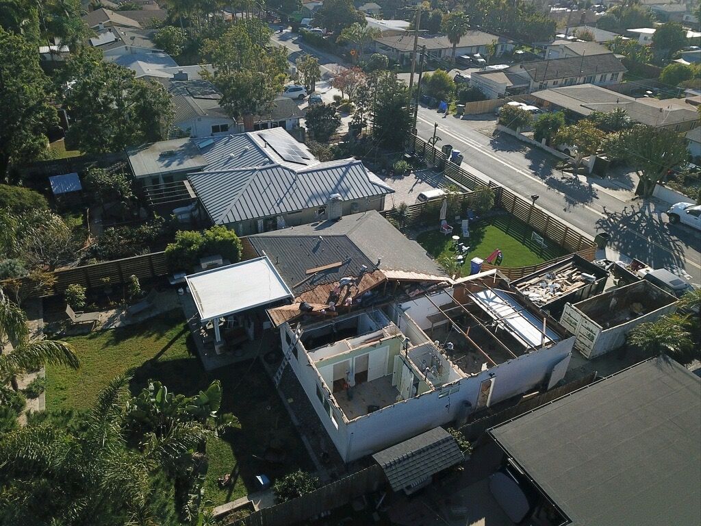 Aerial view of a suburban neighborhood with houses, trees, and streets in bright daylight
