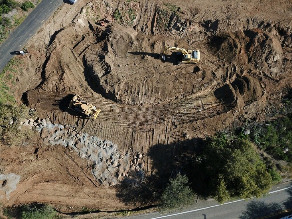 Aerial view of a construction site with earthmoving equipment carving a circular excavation.