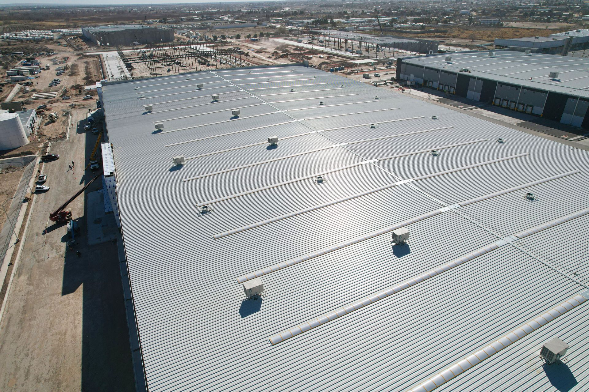 Aerial view of a large industrial building with a ribbed metal roof and numerous ventilation units.