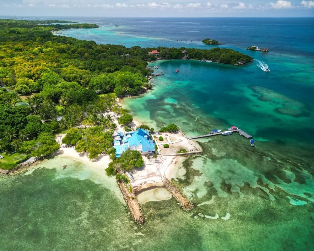 Vista aérea de un complejo turístico con techo azul en una exuberante costa tropical con aguas turquesas