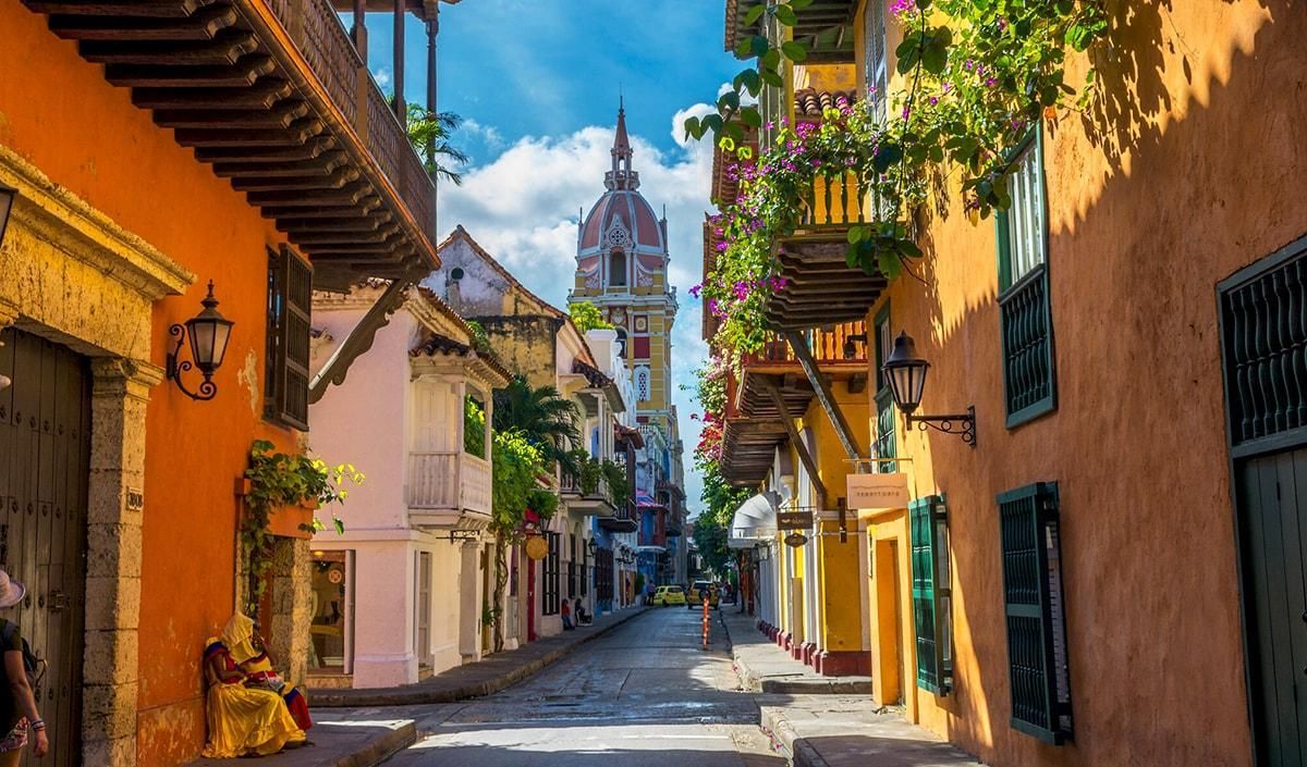 Calle estrecha en Cartagena, Colombia, con edificios coloniales de vibrantes colores naranja y amarillo