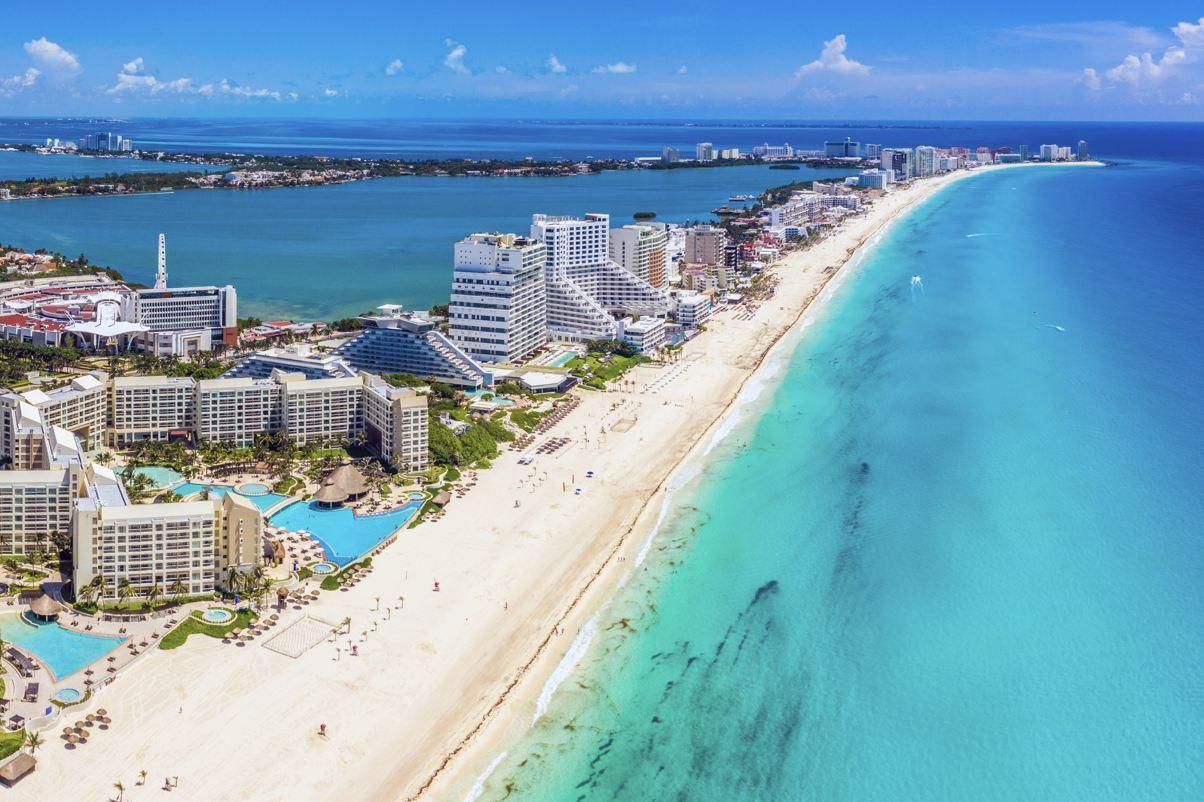 Vista aérea de un complejo turístico tropical con una gran piscina dividida en varias secciones, estructuras con techos