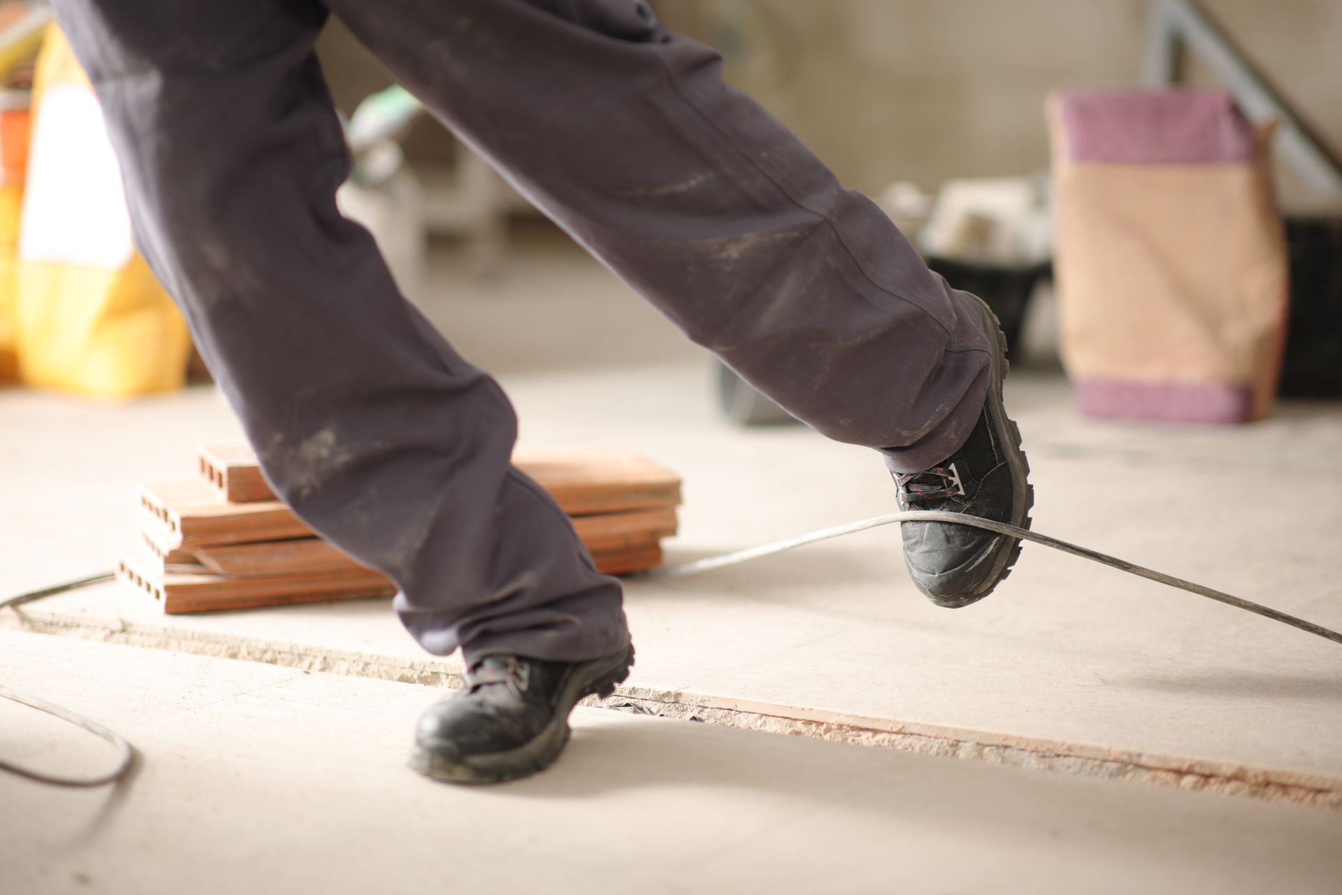 A construction worker stumbling with a cord in a construction site. A construction worker stumbling with a cord in a construction site.