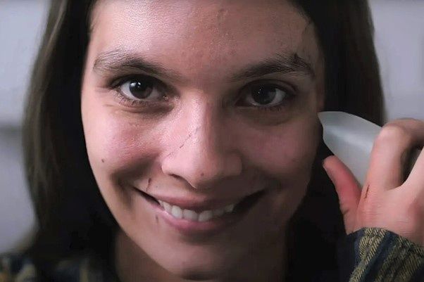 A woman is smiling while holding a white object to her ear.