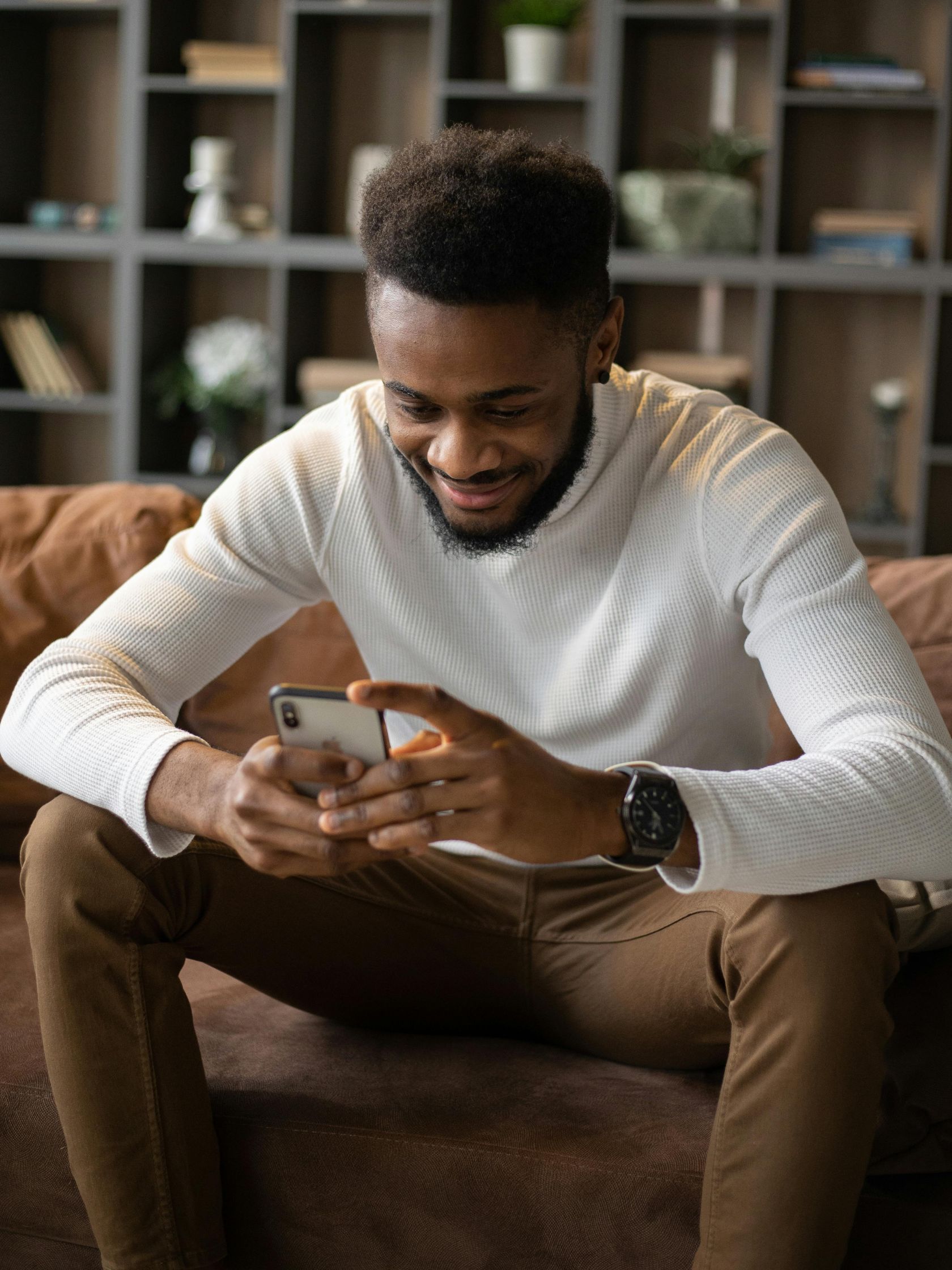 A man is sitting on a couch looking at his phone.