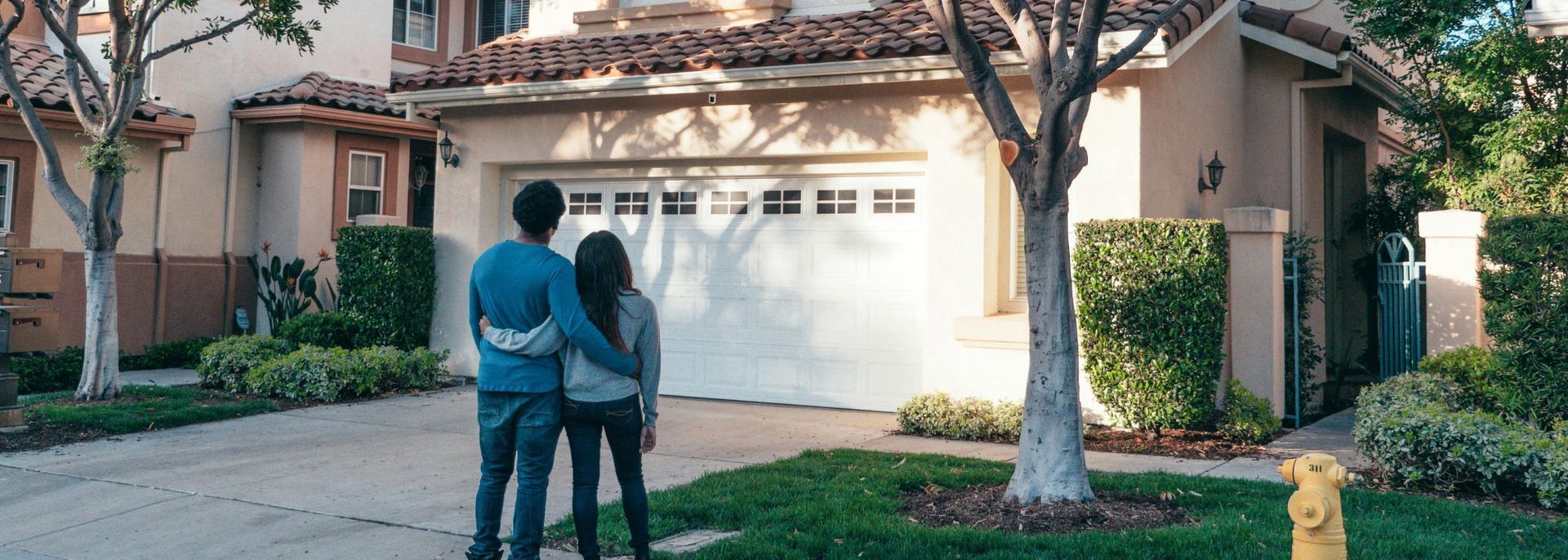 A man and woman are standing in front of a house.