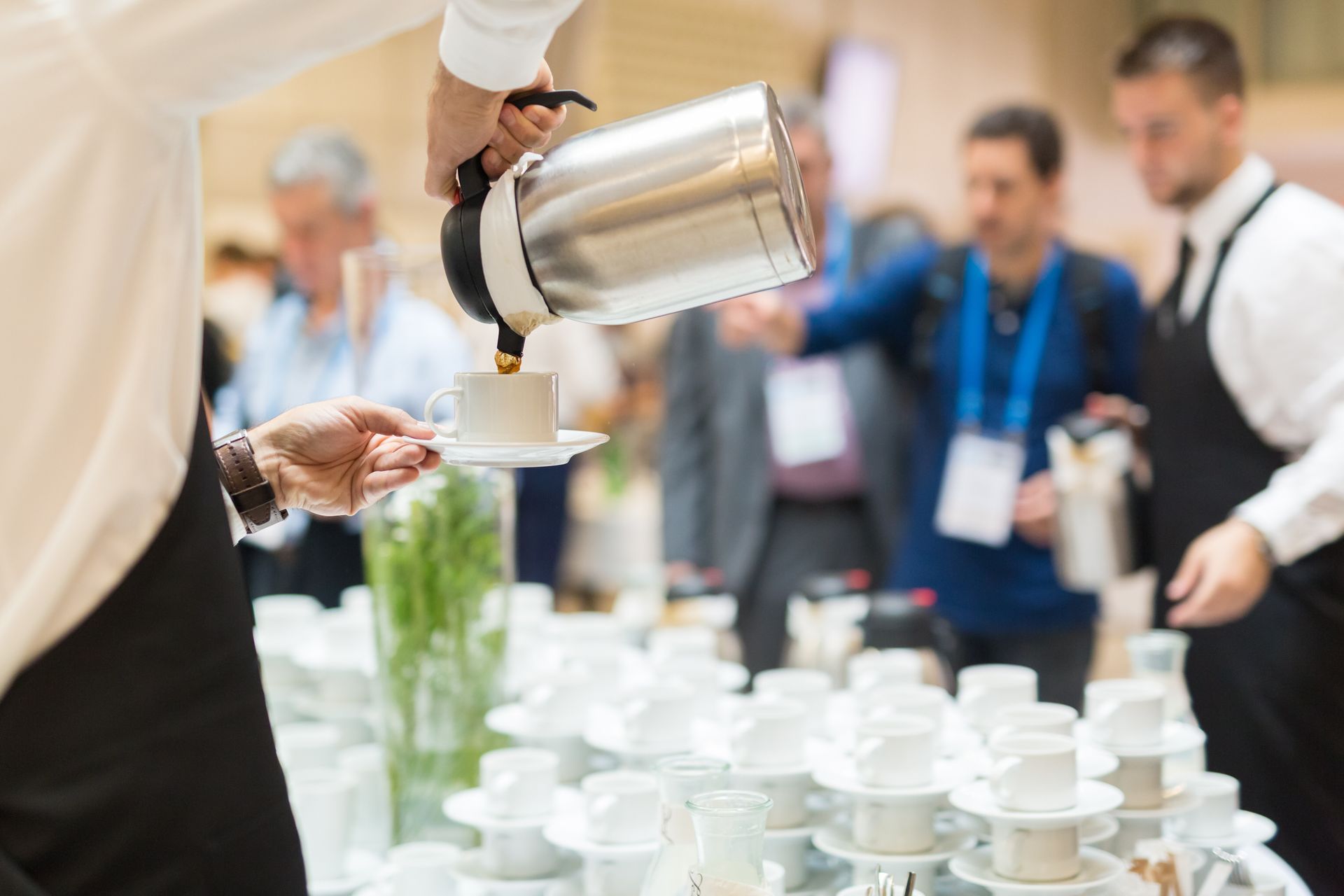 Caterer pouring coffee into cups at a buffet station during a business event