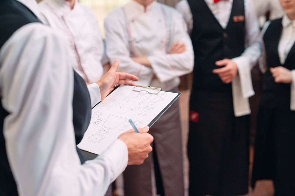Wedding officiant holding a clipboard and pen while speaking to a group in formal attire