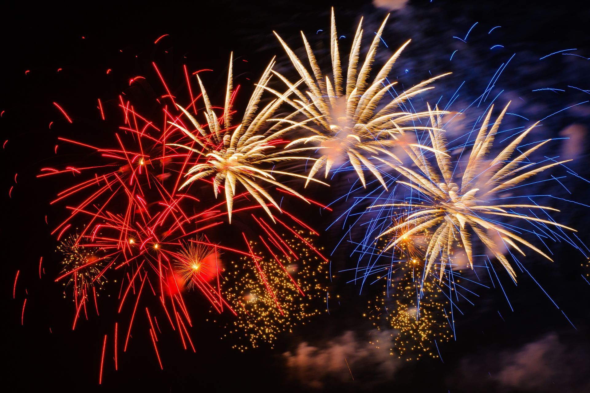 Colorful fireworks bursting in red, gold, and blue against a dark night sky