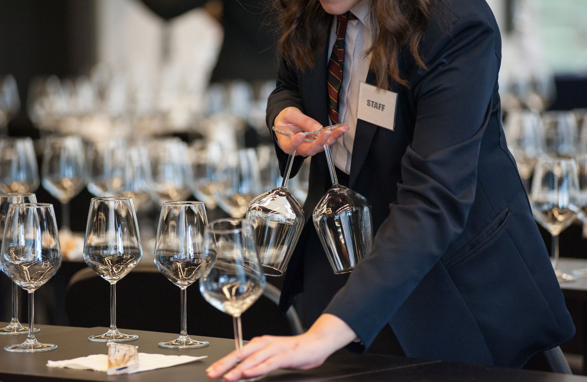 Waiter setting wine glasses at a table in a formal event venue