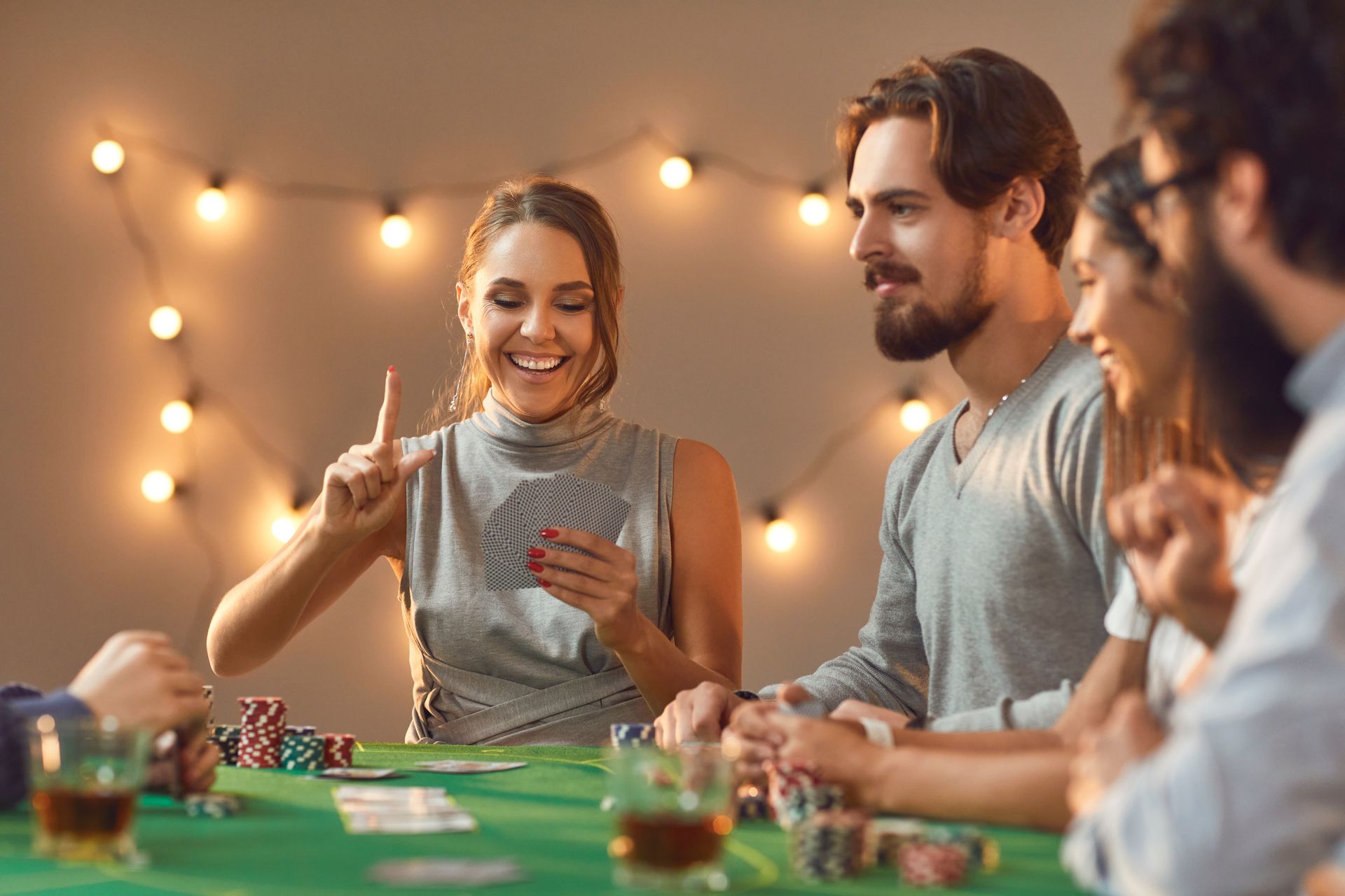 Friends playing a board game at a cozy, warmly lit table with string lights in the background