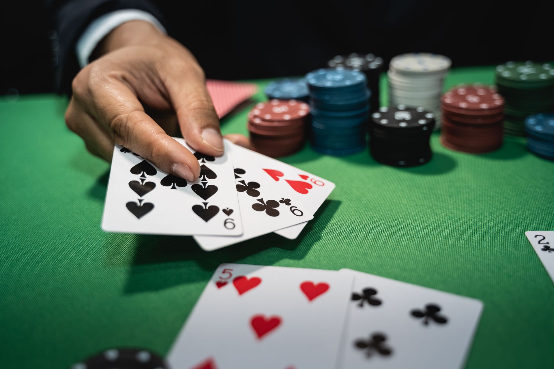 Hand placing cards on a green poker table with chips stacked in the background
