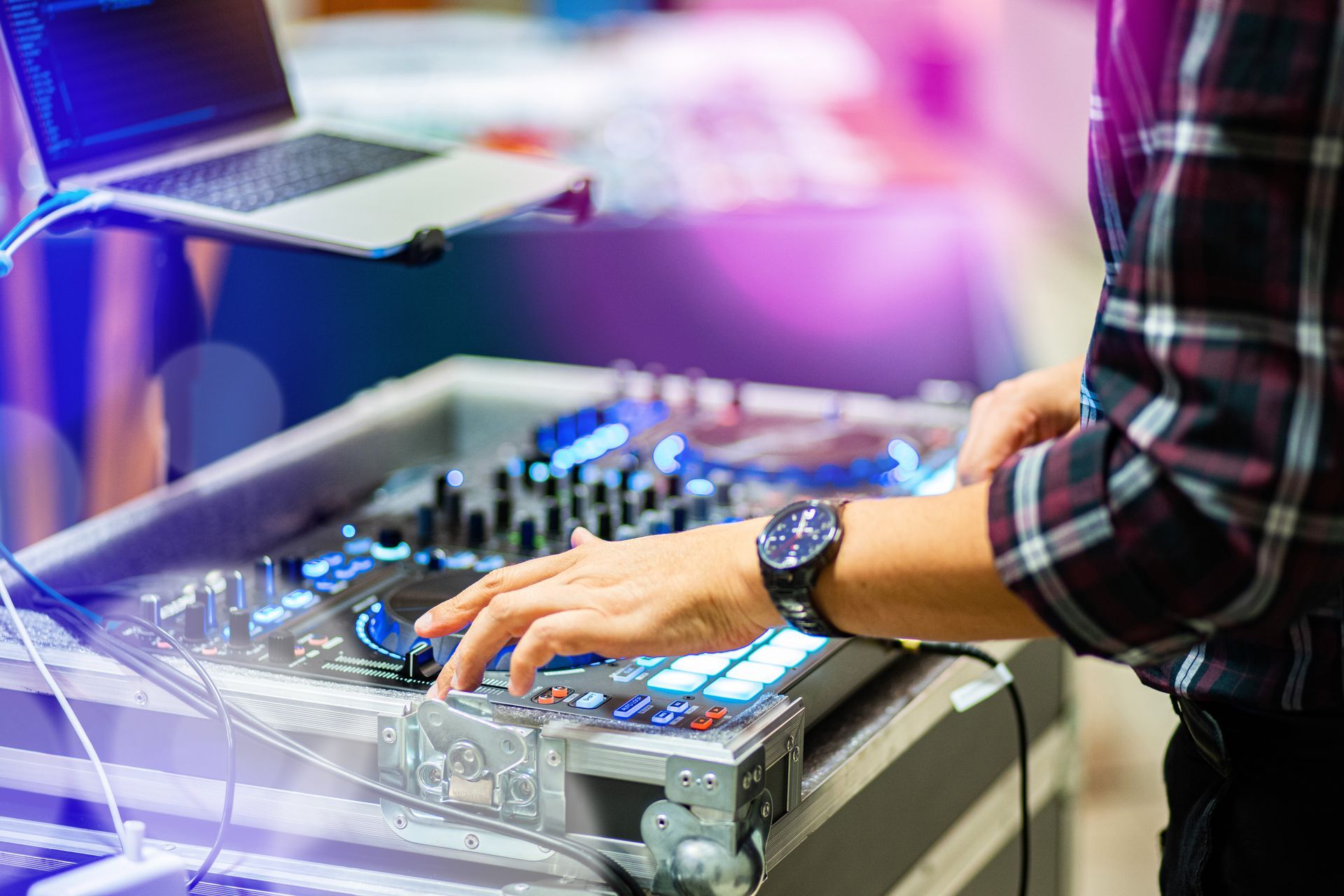 Person using a DJ mixer with glowing controls at a music booth