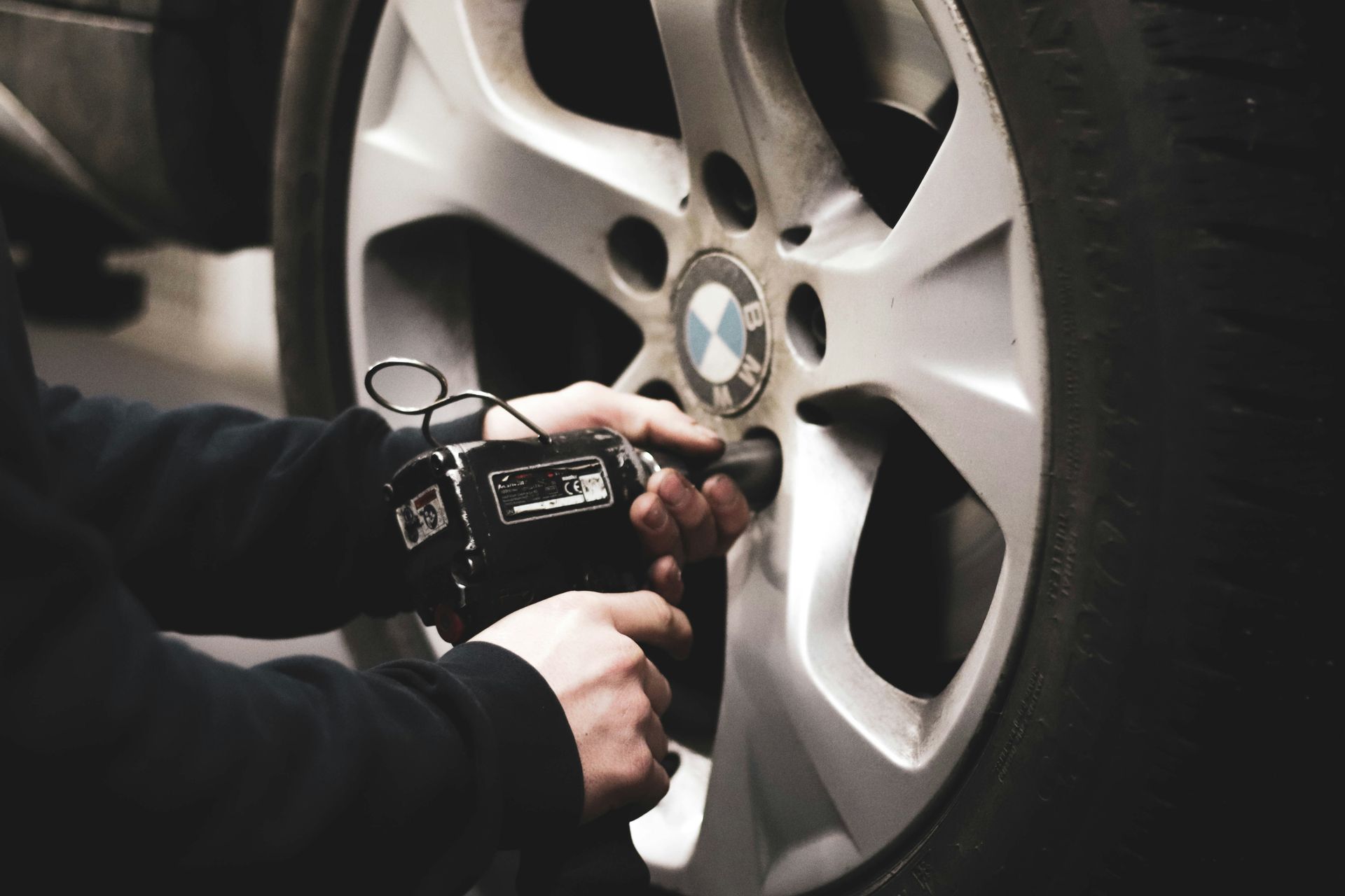 Roadside assistance technician unscrewing a flat tire for tire service