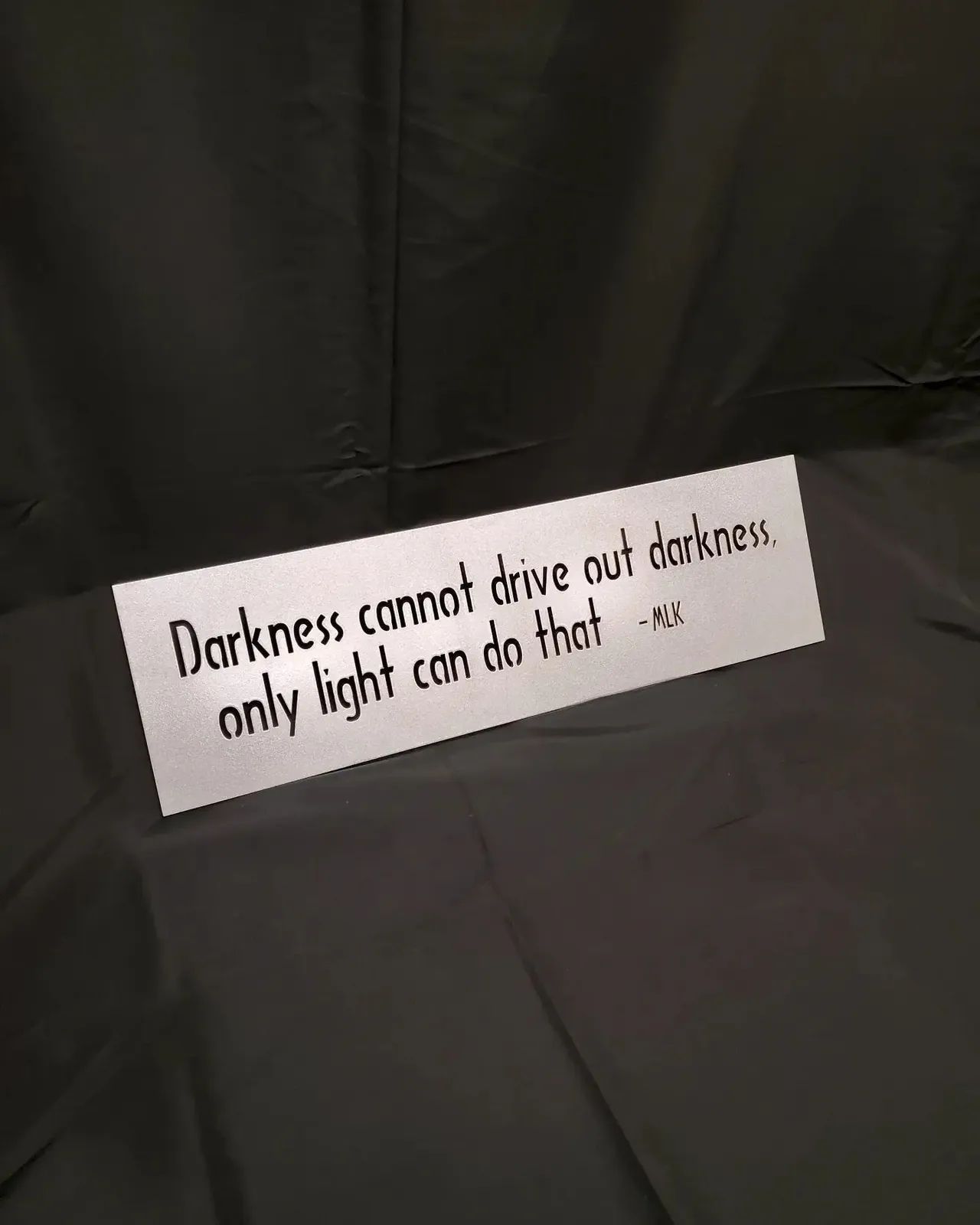 Quote on white sign: “Darkness cannot drive out darkness; only light can do that.”