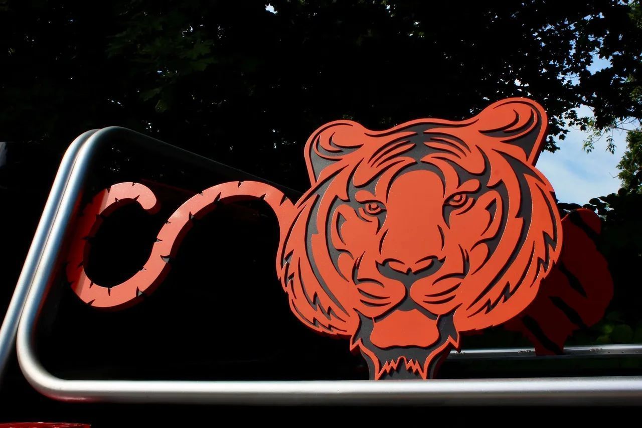 Red tiger graphic on a black vehicle decal, with a chrome bar and dark background.
