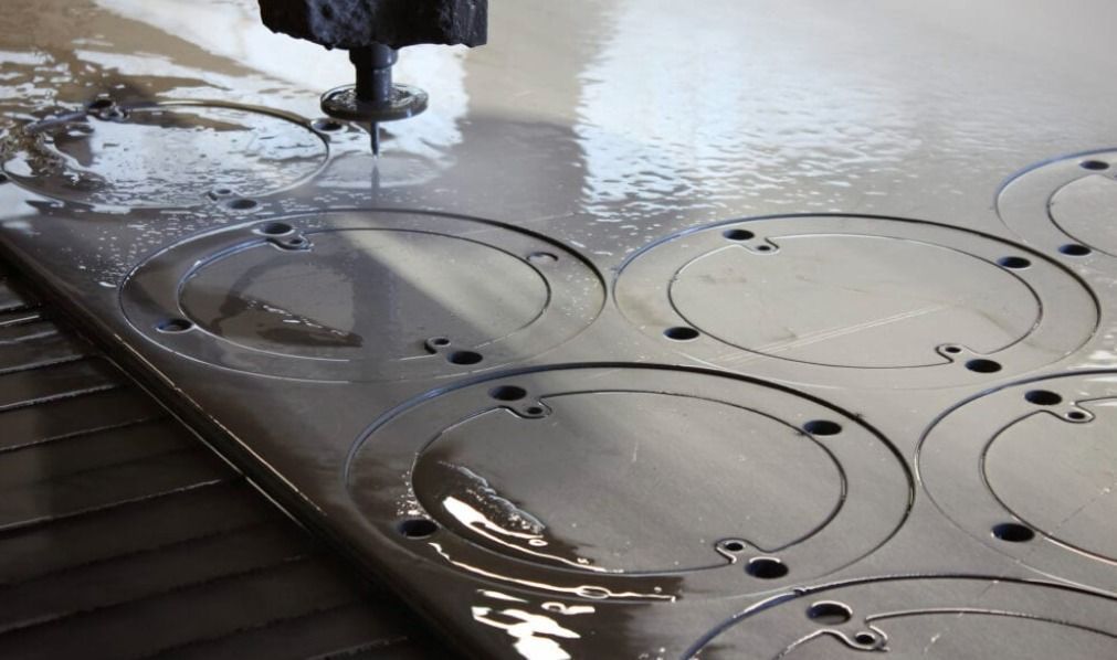 Waterjet cutting metal sheet with circular patterns and water pooling on the surface