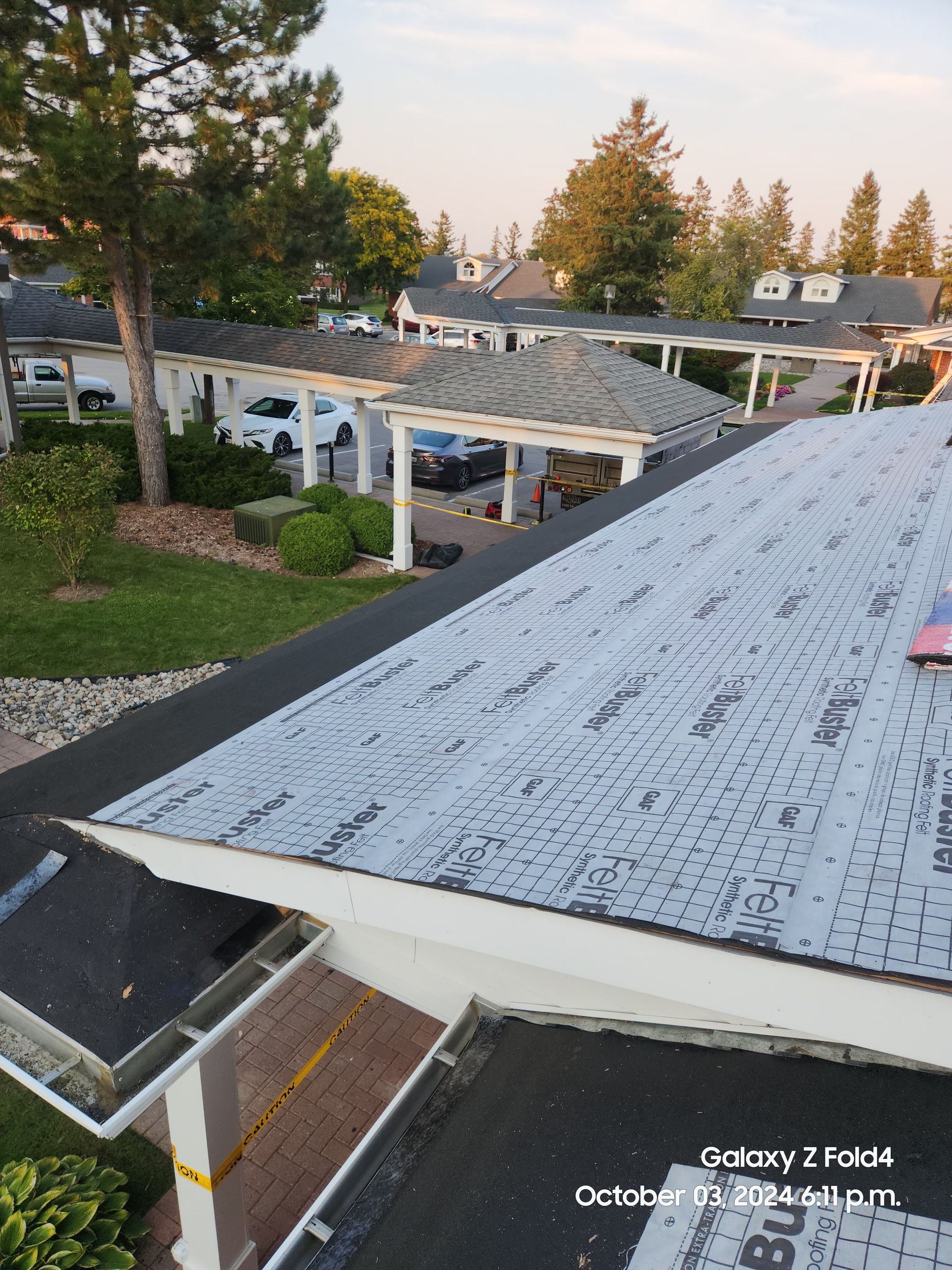 Roof view of a neighborhood with trees, houses, and a covered patio at sunset