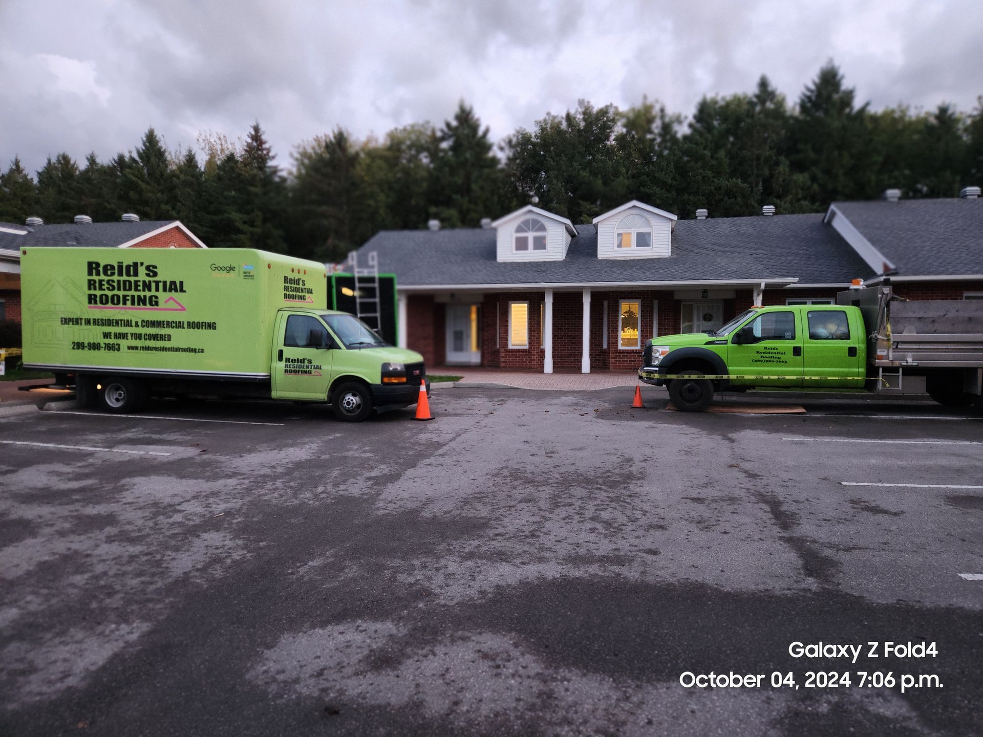 Two green Roto-Rooter service vans parked outside a house on a wet driveway