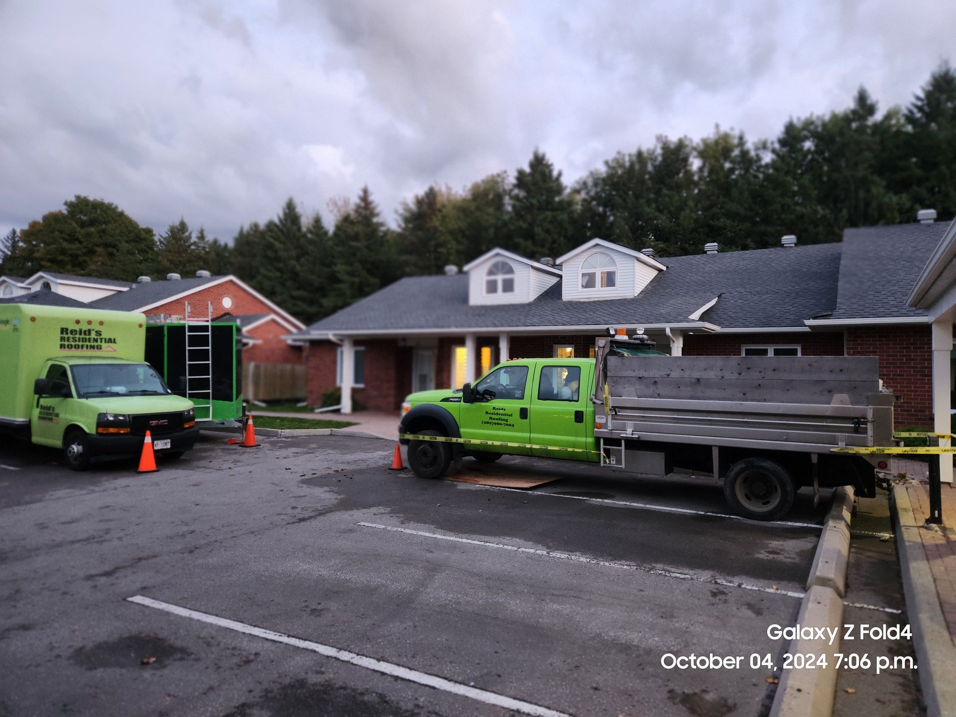 Workers and trucks outside a house with roof damage during repairs