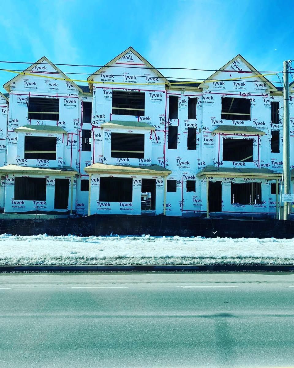 Row of weathered blue-and-white houses with boarded windows along a snowy roadside