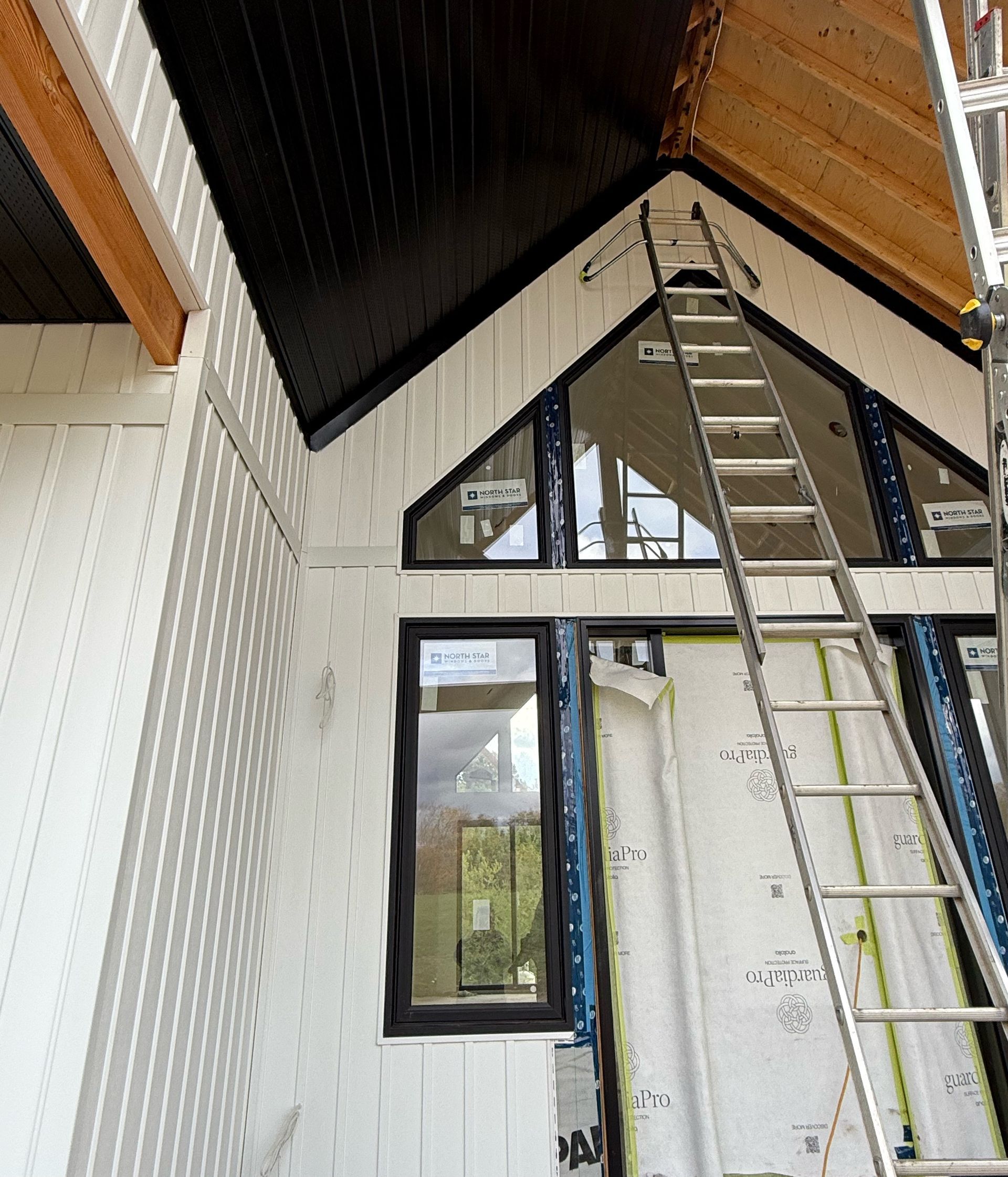 Interior with ladder reaching a high triangular ceiling and loft window in a white room