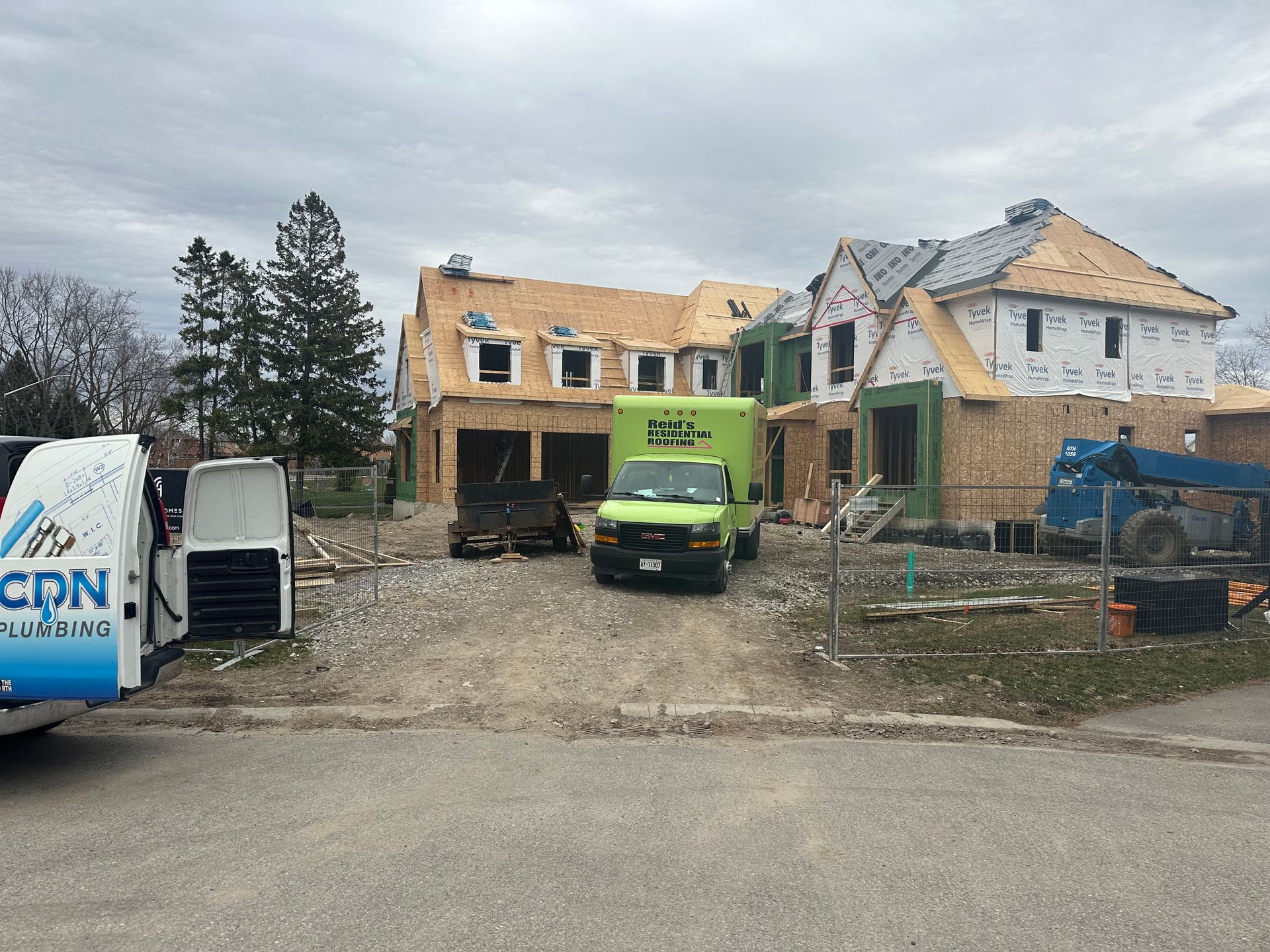 Construction site with two houses under renovation and a green truck in front