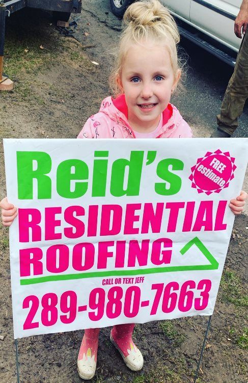 Child holding a Reid’s Residential Roofing sign with phone number 289-980-7663
