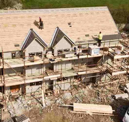 Workers on scaffolding repairing a roof with two dormer windows