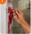Hand pressing a red fire alarm pull station on a wall