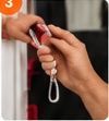 Hands attaching a pink safety strap to a white rope loop on a door handle.