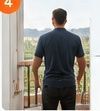 Man in dark shirt standing at an open doorway, looking out at a bright balcony or patio